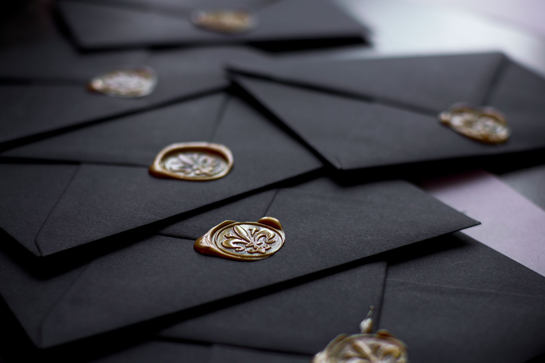 Black envelopes closed with gold wax seals as part of a stationery set